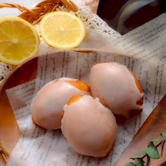 白いグレーズがかかった丸いレモンケーキ3個と、カットしたレモンが添えられた様子